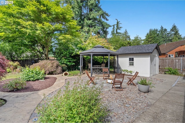 view of yard with a storage shed, a fenced backyard, an outbuilding, and a gazebo