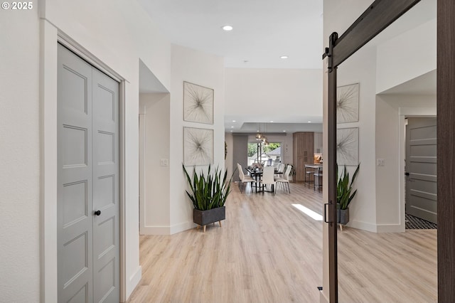 foyer entrance featuring light wood-style floors, a barn door, baseboards, and recessed lighting