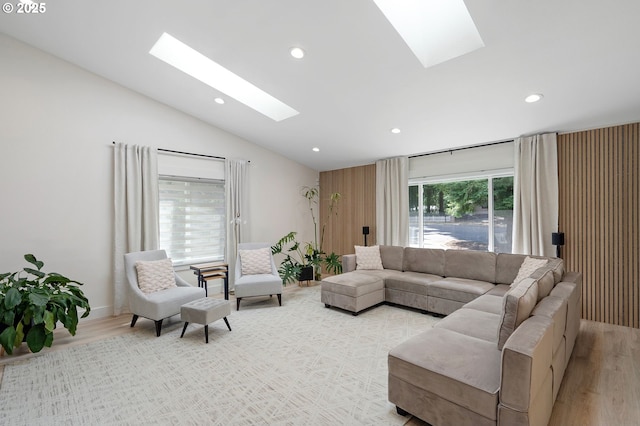 living room with light wood-type flooring, vaulted ceiling with skylight, and recessed lighting