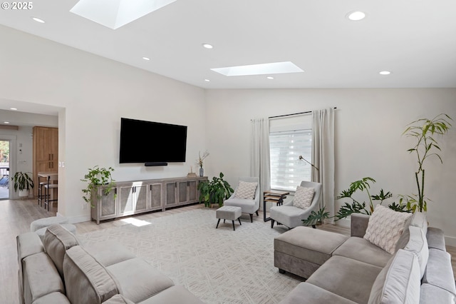 living area featuring light wood-type flooring, vaulted ceiling with skylight, and recessed lighting