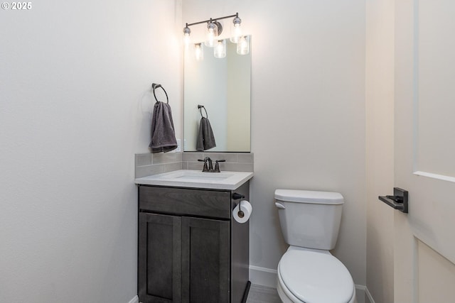 half bathroom with vanity, baseboards, and toilet