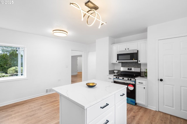 13332 SE Harold St, Portland, OR 97236 - kitchen with appliances with stainless steel finishes, light wood-style flooring, white cabinets, a center island, and backsplash