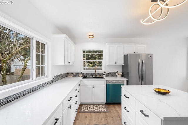 13332 SE Harold St, Portland, OR 97236 - kitchen featuring dishwasher, freestanding refrigerator, a sink, light wood finished floors, and white cabinetry