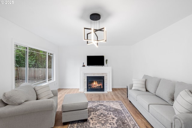 13332 SE Harold St, Portland, OR 97236 - living room with light wood finished floors, a chandelier, a fireplace, and baseboards