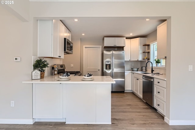 4106 SE 122nd Ave, Portland, OR 97236 - kitchen featuring appliances with stainless steel finishes, open shelves, light wood finished floors, a peninsula, and recessed lighting