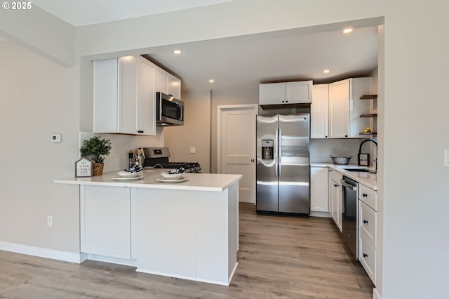 4106 SE 122nd Ave, Portland, OR 97236 - kitchen with stainless steel appliances, open shelves, a peninsula, light wood-type flooring, and recessed lighting