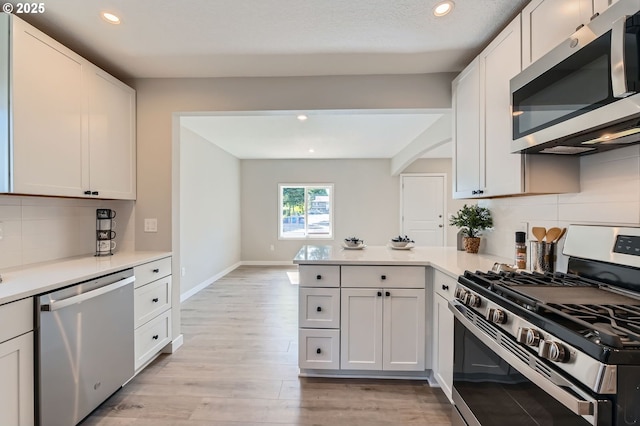 4106 SE 122nd Ave, Portland, OR 97236 - kitchen featuring stainless steel appliances, a peninsula, backsplash, light wood-style flooring, and recessed lighting
