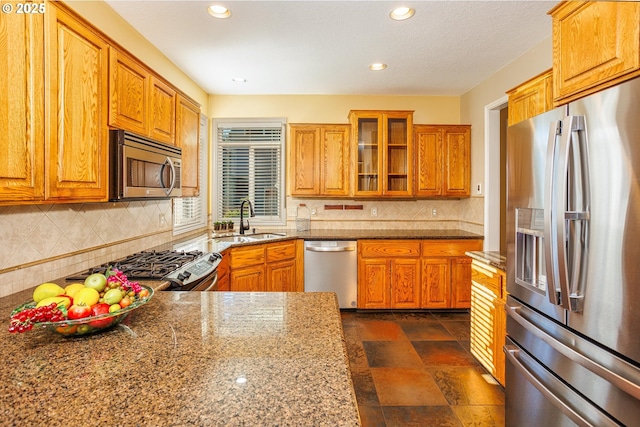 kitchen with sink, backsplash, stainless steel appliances, and stone counters