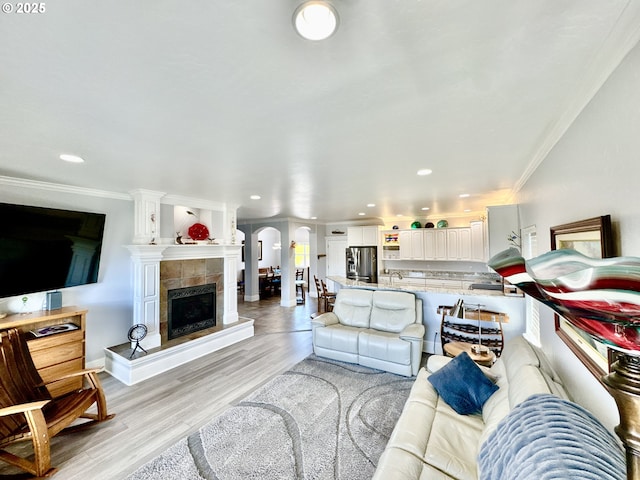 842 Chetco Point Ter, Brookings, OR 97415 - living room featuring crown molding, light wood-style floors, a tile fireplace, arched walkways, and recessed lighting