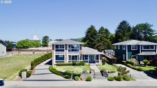 842 Chetco Point Ter, Brookings, OR 97415 - view of front of property featuring stone siding, a front yard, and a balcony