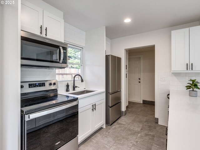 kitchen with stainless steel appliances, a sink, white cabinetry, light countertops, and tasteful backsplash