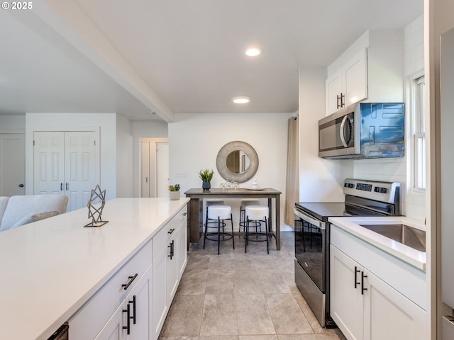 kitchen featuring stainless steel appliances, white cabinets, light countertops, recessed lighting, and baseboards