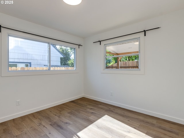 spare room with baseboards and wood finished floors