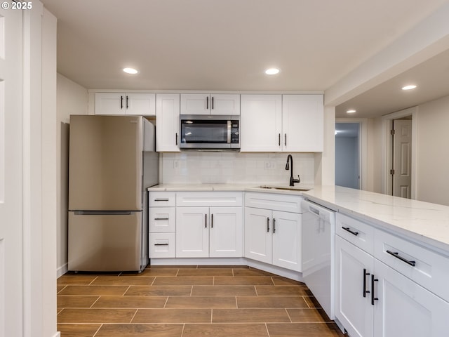 kitchen featuring stainless steel appliances, a sink, white cabinets, decorative backsplash, and recessed lighting