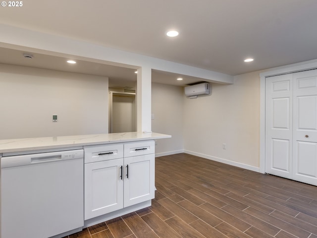 kitchen featuring white dishwasher, an AC wall unit, white cabinetry, baseboards, and light stone counters