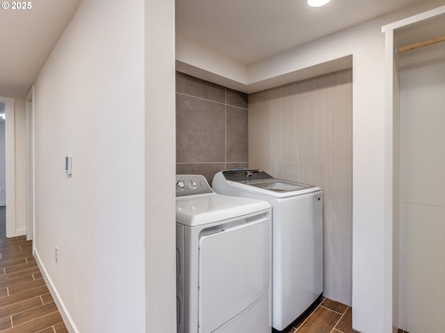 laundry room featuring independent washer and dryer, tile walls, and dark wood finished floors