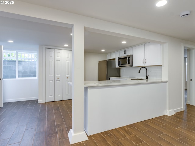 kitchen with appliances with stainless steel finishes, a sink, dark wood-style flooring, white cabinetry, and recessed lighting