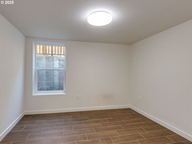 spare room featuring dark wood-type flooring and baseboards