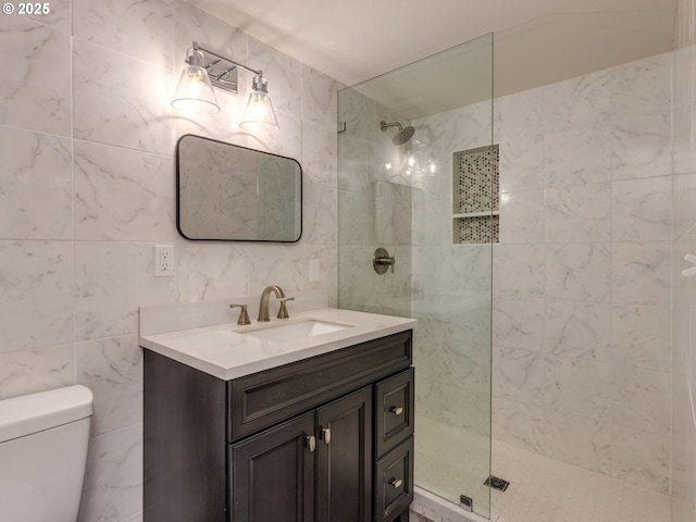 bathroom with walk in shower, vanity, toilet, and tile walls