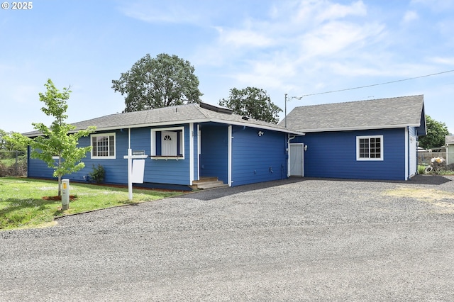ranch-style house with gravel driveway, a front lawn, and a shingled roof