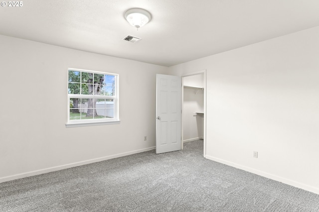 unfurnished bedroom featuring carpet flooring, baseboards, and a spacious closet