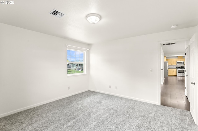 empty room featuring dark carpet, baseboards, and a smoke detector