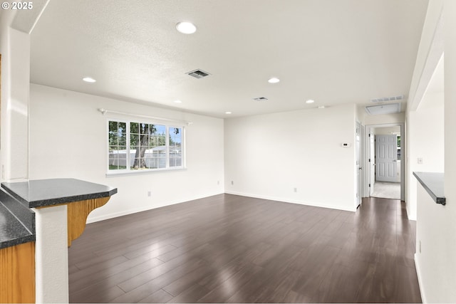 unfurnished living room with dark wood finished floors, recessed lighting, and baseboards