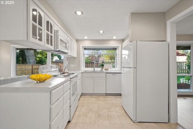 kitchen featuring a sink, glass insert cabinets, white appliances, and a healthy amount of sunlight