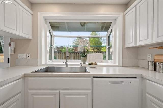 kitchen with light countertops, white dishwasher, white cabinetry, and a sink