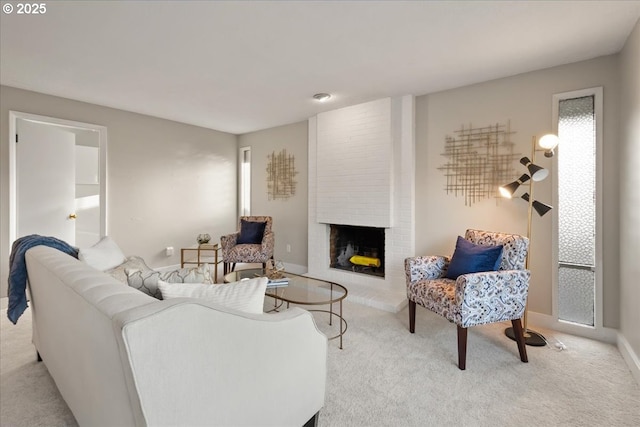 carpeted living area featuring baseboards and a brick fireplace