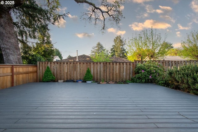 deck at dusk featuring a fenced backyard