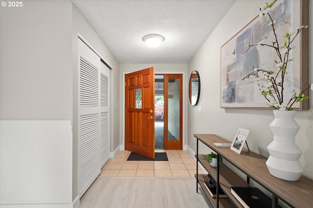 foyer with baseboards and a textured ceiling