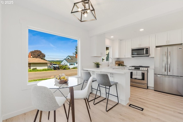 kitchen featuring a sink, light countertops, white cabinets, light wood finished floors, and stainless steel appliances