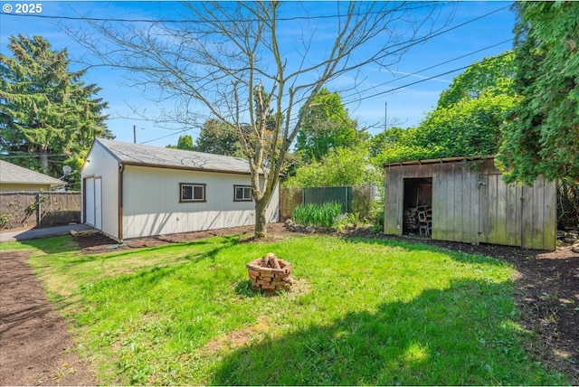 view of yard with fence, an outdoor structure, and an outdoor fire pit