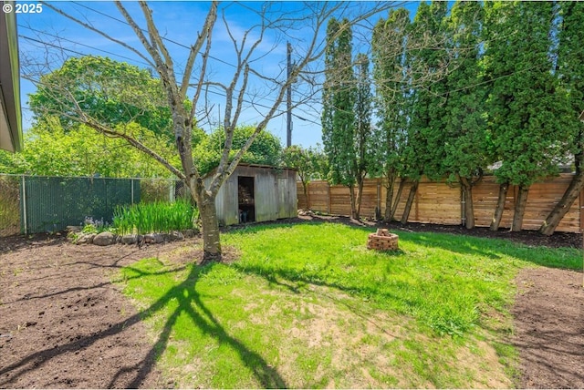 view of yard with an outbuilding, a shed, a fenced backyard, and an outdoor fire pit