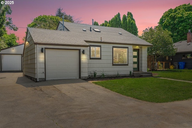 ranch-style house featuring roof with shingles, a yard, and concrete driveway