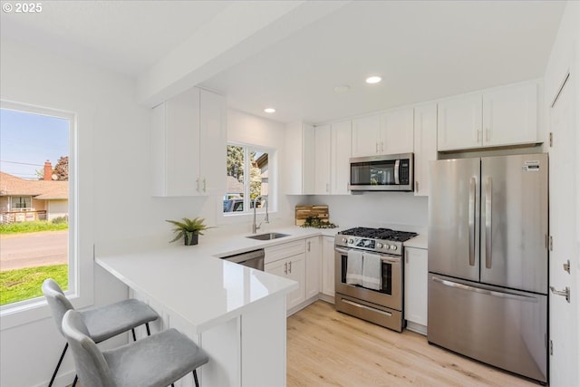 kitchen with a sink, white cabinetry, appliances with stainless steel finishes, and light countertops