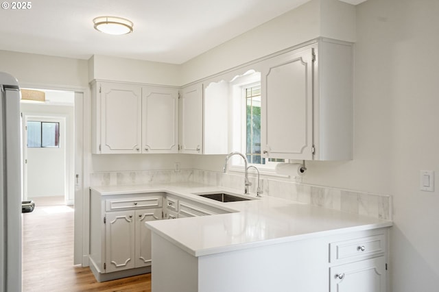 kitchen featuring light countertops, wood finished floors, a sink, and a wealth of natural light