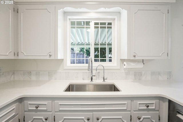 kitchen featuring light countertops, a sink, and white cabinetry