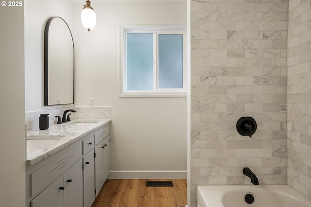 full bathroom featuring double vanity, visible vents, a sink, wood finished floors, and baseboards