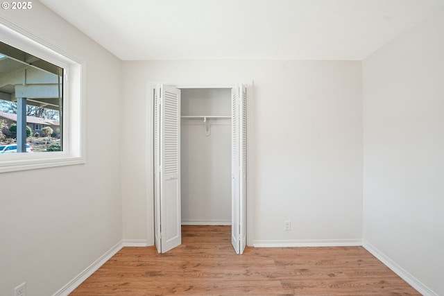 unfurnished bedroom featuring a closet, light wood-type flooring, and baseboards