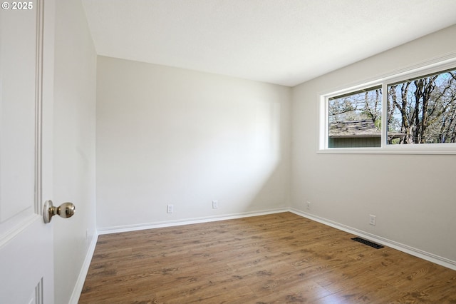 empty room featuring visible vents, baseboards, and wood finished floors