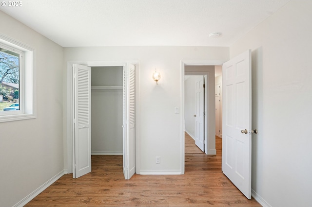 unfurnished bedroom with light wood finished floors, baseboards, and a closet