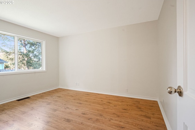 unfurnished room featuring baseboards, visible vents, and light wood-style floors