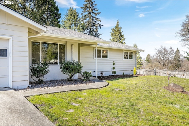 exterior space with a shingled roof, a front yard, fence, and a garage