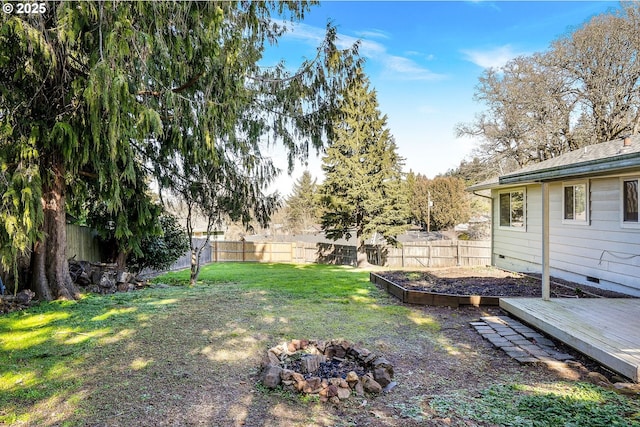 view of yard featuring an outdoor fire pit, a deck, and a fenced backyard