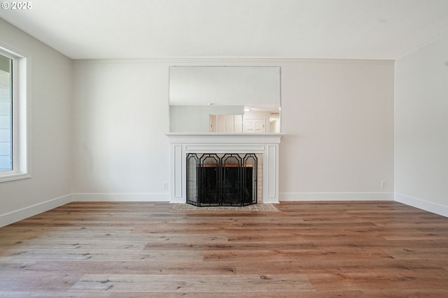 unfurnished living room featuring a fireplace, baseboards, and wood finished floors