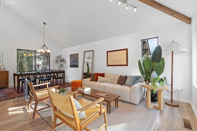 living room with vaulted ceiling with beams, a chandelier, and light wood-type flooring