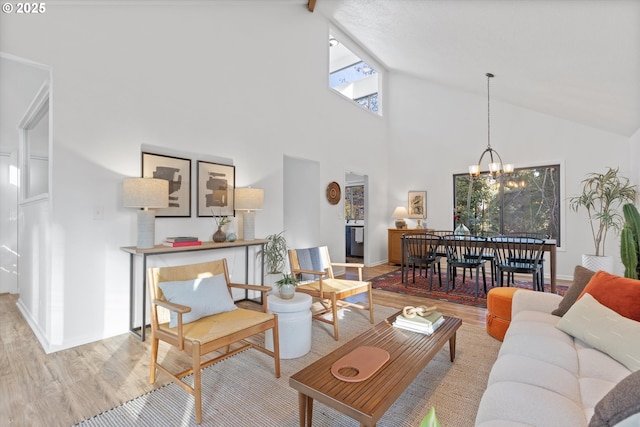 living room featuring high vaulted ceiling, a healthy amount of sunlight, a notable chandelier, and light wood-type flooring