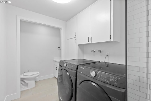 laundry room featuring cabinets, washing machine and dryer, and light tile patterned flooring